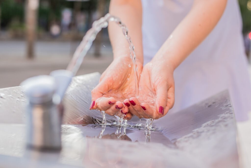 closeup on woman hand catching water. splashing drops on sunny s