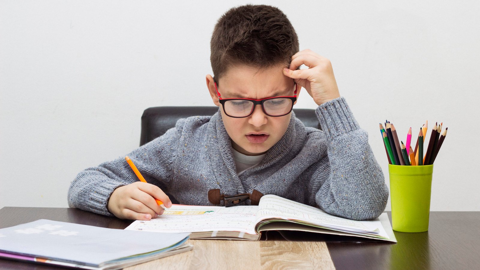 young boy frustrated over homework, writing at home. boy studying at table. kid drawing with a pencil
